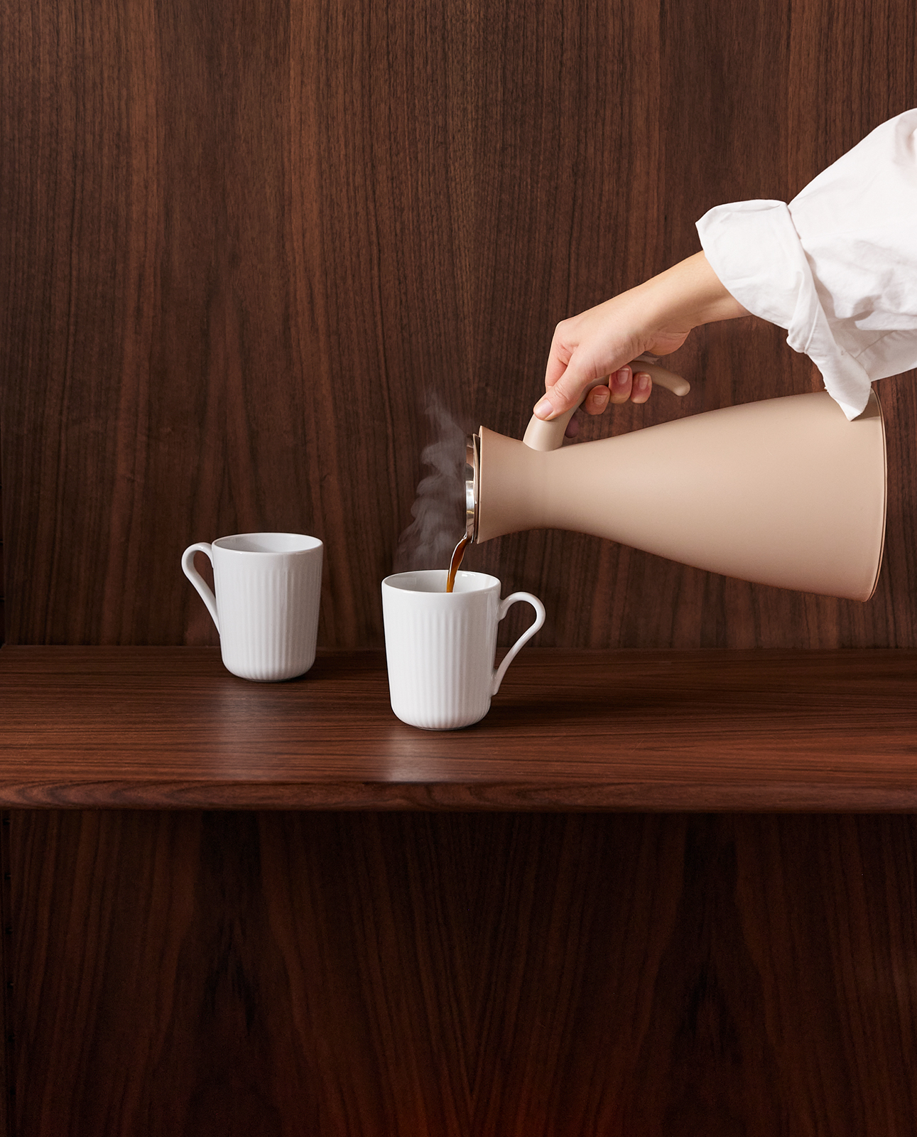 Die Legion Nova Becher auf einem Holzbrett. In einen der Becher wird gerade Kaffee eingegossen.