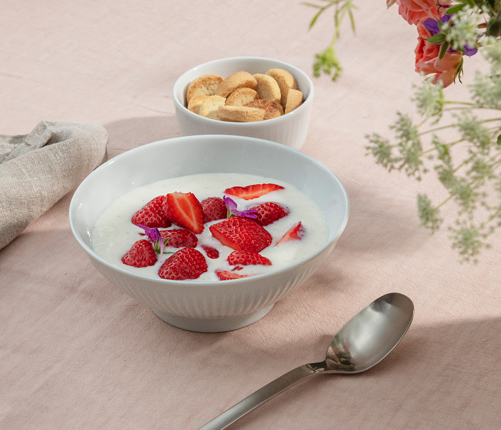 Ein gedeckter Frühstückstisch, auf dem die mit Cerealien und Erdbeere gefüllte Scahle steht.