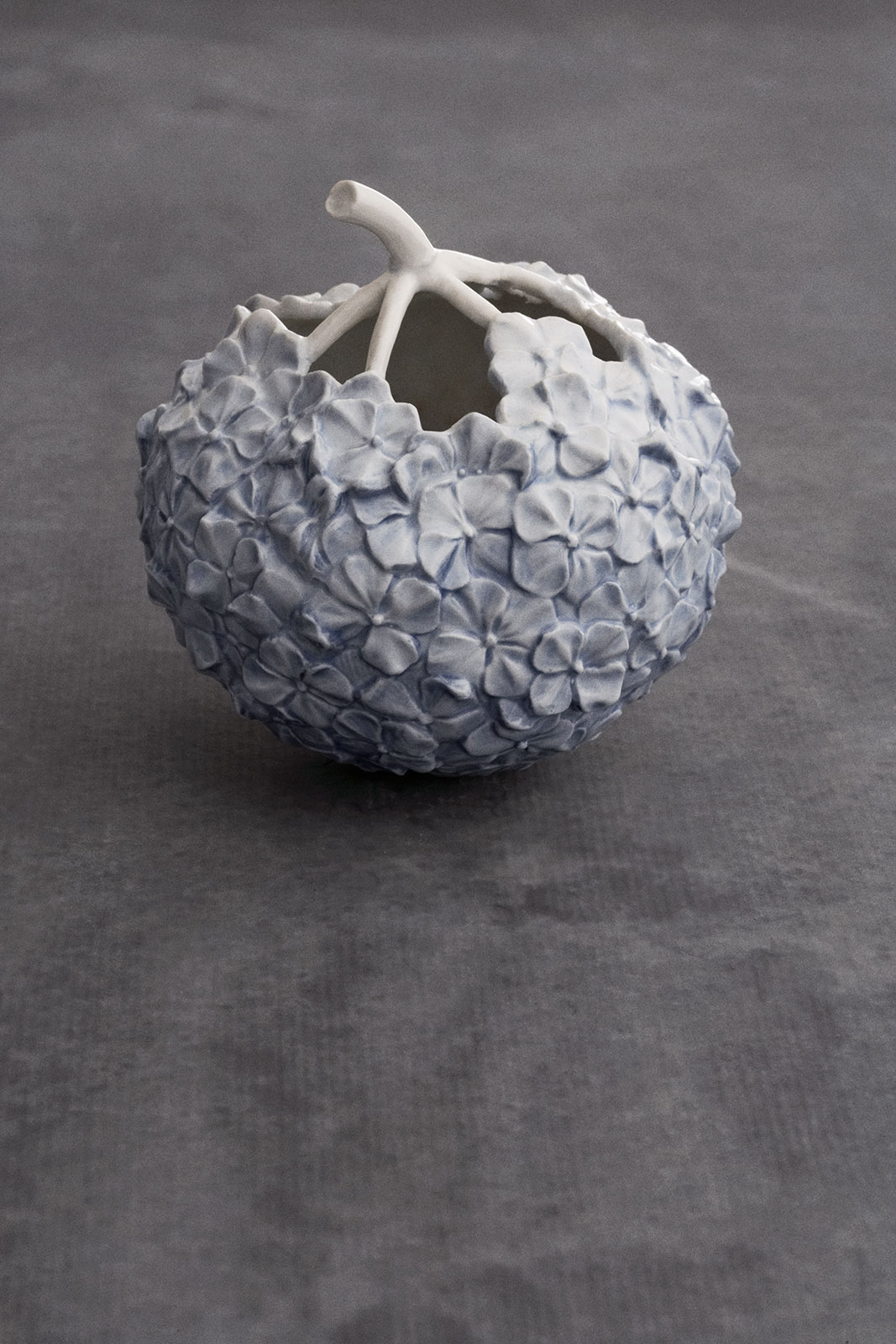 Die Hortensien Vase hellblau auf einem minimalistischen Betonuntergrund.