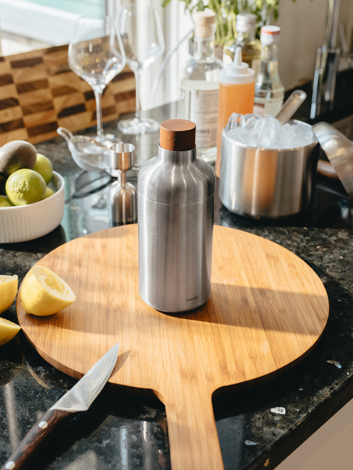 Nahaufnahme einer Küchenzeile, auf der sich der Liquid Lounge Cocktailshaker befindet. Um das Produkt herum sind Zubereitungsutensilien für Cocktails.