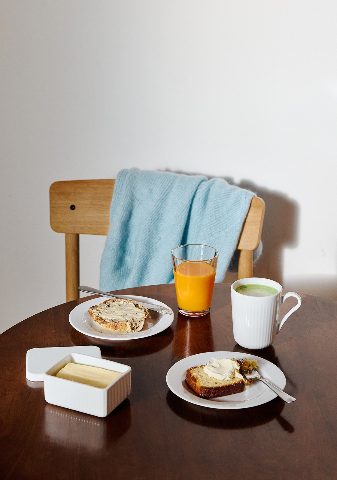 Ein gedeckter Frühstückstisch mit zwei Legio Nova tellern und geschmierten Butterbroten sowie weiteren Artikeln der Eva Trio Geschirrserie.