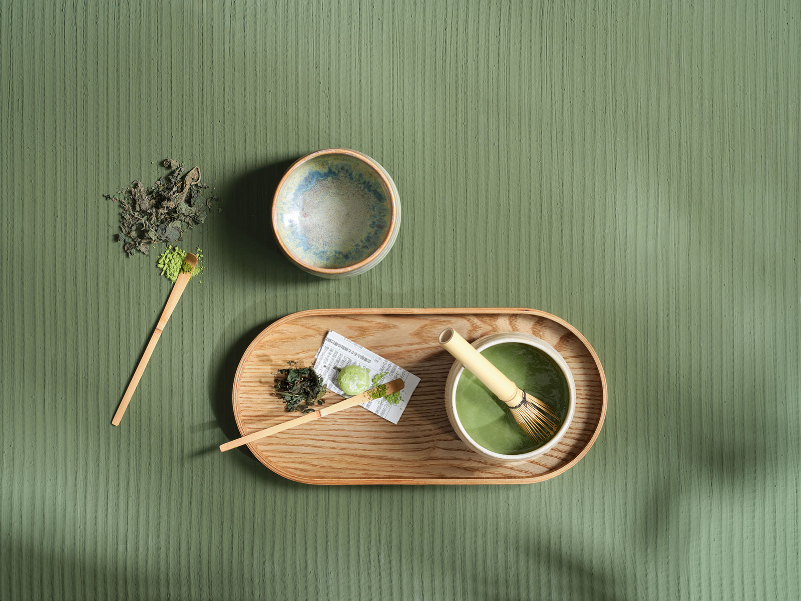 Draufsicht auf ein Matcha-Zubereitungs-Stillleben mit Matcha Schüsseln, Matcha Besen und Matcha Löffel.