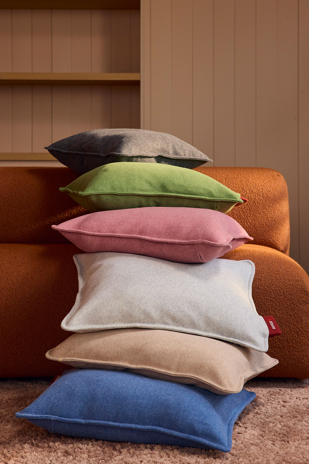 Wasserfallartig ergießen sich Ploov Heizkissen aller Farben ober die Sitzkissen einer Couch heraus auf den Boden.