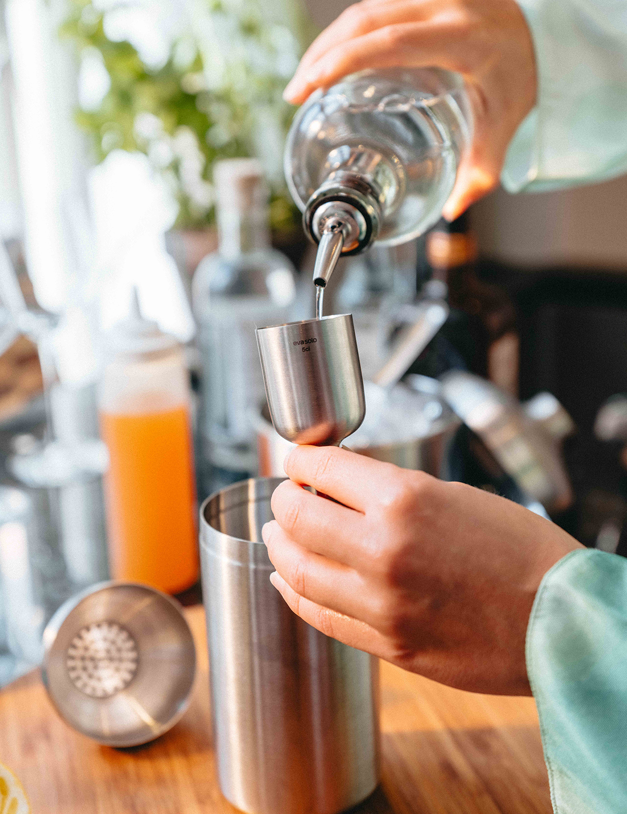 Nahaufnahme, wie auf einer Arbeitsfläche Flüssigkeit in den Cocktail-Messbecher gegeben wird.