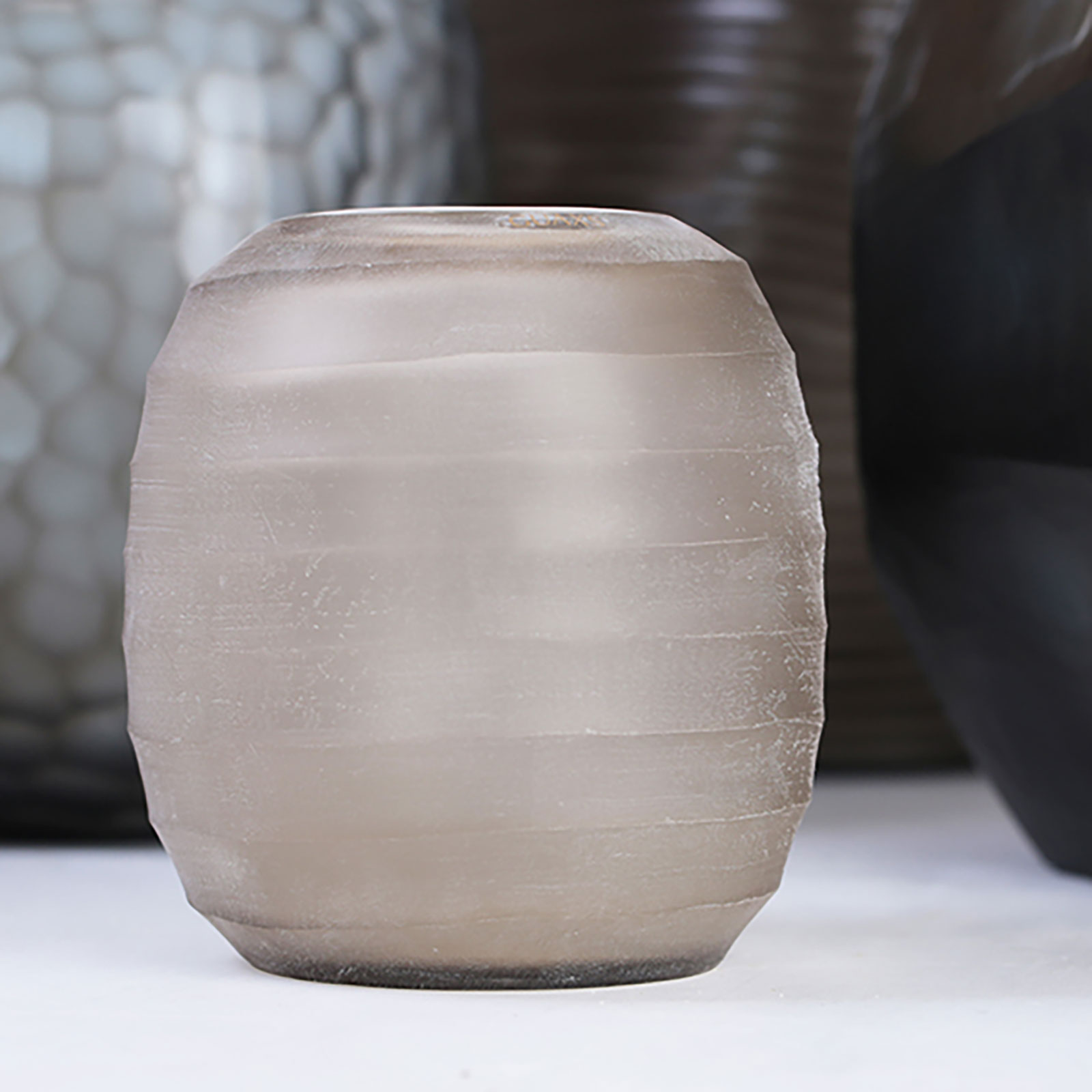 Die Belly Vase smokegrey von Guaxs steht mit aneren Vasen auf einem Tisch.