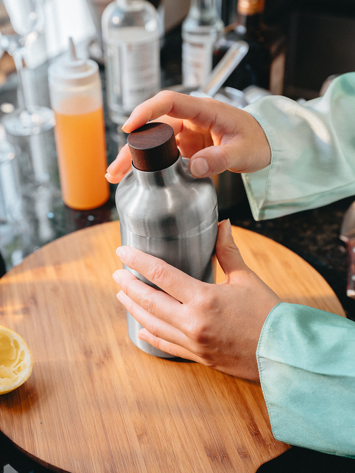 Eine Küchenzeile, auf der sich der Cocktailshaker befindet, dessen Holzdeckel gerade auf den Shaker gesetzt wird.